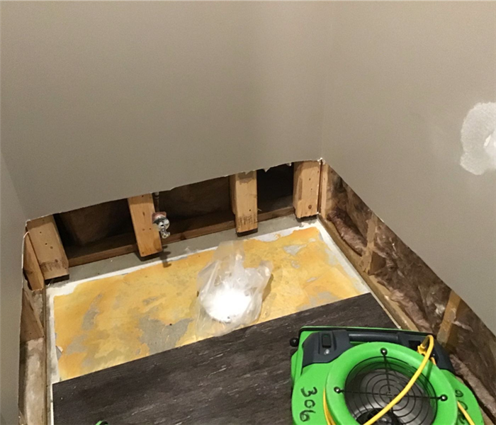 Basement bathroom with a portion of the vinyl plank and drywall removed.