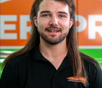 Long brown hair with beard in front of SERVPRO truck