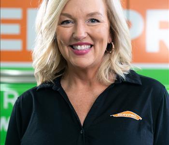 Blonde lady with white top w/ SERVPRO logo on wall