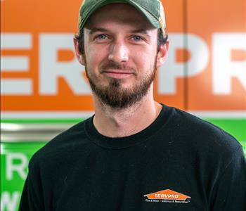 Brown hair with beard with baseball hat in front of SERVPRO truck