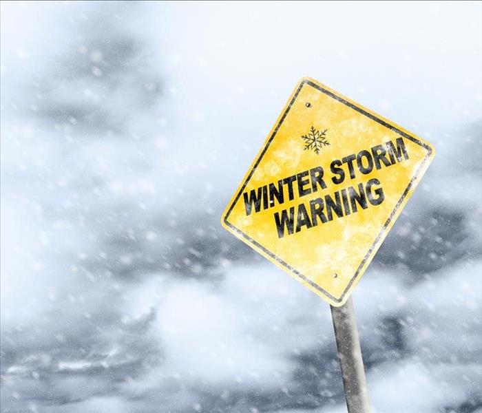 A picture of a warning sign saying "Warning: Winter Storm" in the middle of falling snow.