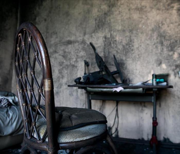A blackened chair in a room with smoke-blackened walls.