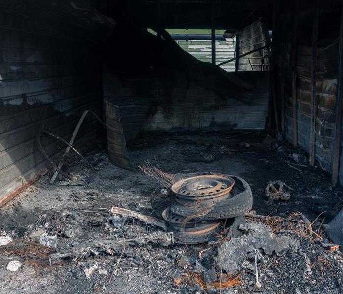 Fire damage in a small one-stall garage, including burned tires and a tool wall.